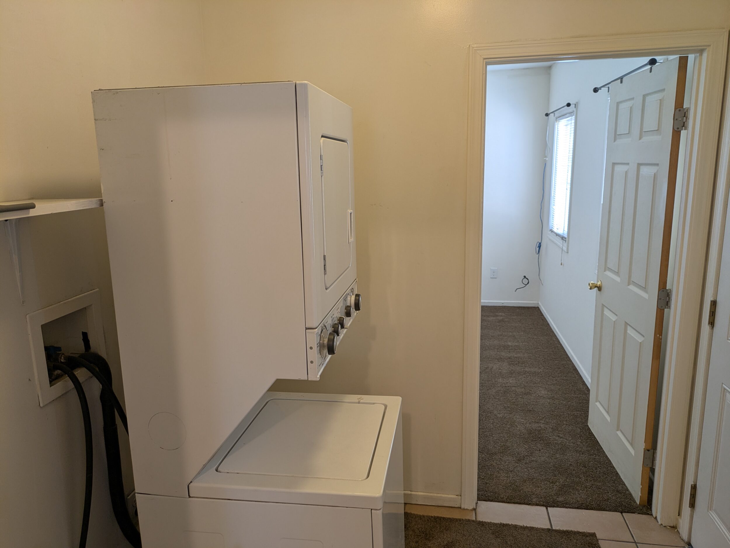 Utility room with stacking washer/dryer, bedroom door